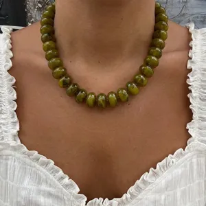 Close-up detail of bohemian olive green resin beaded necklace with marbled texture on model