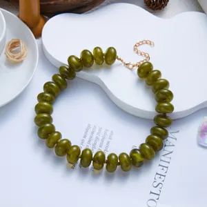 Detail view of olive green resin beaded necklace with gold-tone extension chain.