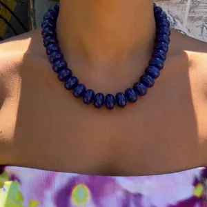 Detailed shot of a navy blue resin beaded necklace in bohemian style on model's neck