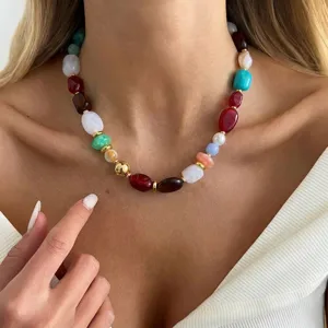 Detailed close-up of a colorful irregular resin bead necklace with gold accents on model.