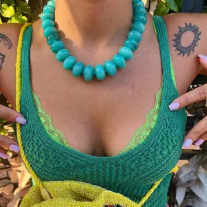 Close-up of bohemian teal resin beaded necklace worn by a model in natural sunlight