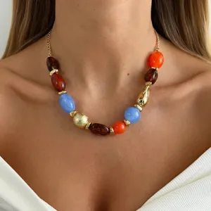Close-up of colorful resin beaded necklace with irregular gold and marbled beads on model.