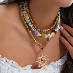 Detalle macro del collar con colgante de sol bohemio y conjunto de cuentas de seda floral