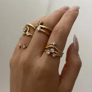 Nahaufnahme goldener geometrischer Wellenringe mit Zirkonia-Steinen an einer Hand