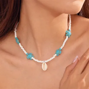 Detail of bohemian white seed bead necklace with turquoise turtle and cowrie shell pendant.