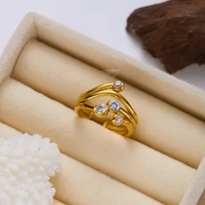 Nahaufnahme eines vergoldeten Edelstahlrings mit gewellten Linien und vier Zirkonias
