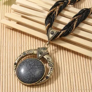 Dettaglio ravvicinato della collana vintage bohémien con grande ciondolo in pietra.