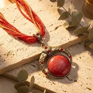 Primo piano di collana vintage bohémien con grande gemma rossa e perline di semi rosse