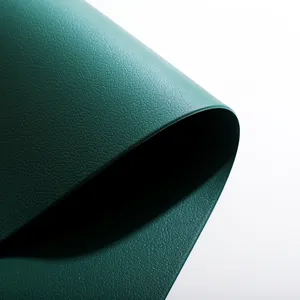 Close-up detail of dark green leather placemat showing fine texture and heat resistance.