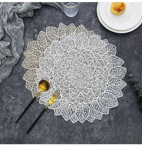Dettaglio del tovaglietta in PVC intagliato e dorato con elegante motivo a foglia allestito.