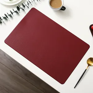 Close-up detail of the dark red leather place mat, showing fine surface texture on white table.