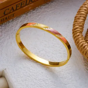 Close-up van goudkleurige roestvrijstalen armband met gekleurd emaille en strass.