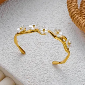 Detaillierte Nahaufnahme eines goldenen Blumen-Armreifs mit fünf weißen Blütenmotiven