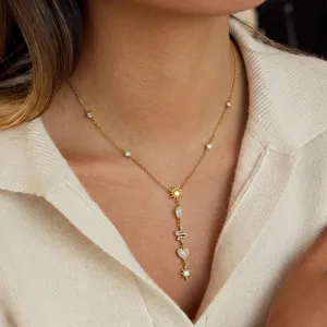 Close-up of elegant gold Y-shaped necklace with star and snake charms on a model