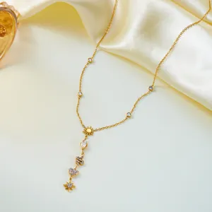 Detailed macro view of gold Y-shaped necklace featuring heart and eight-pointed star pendants