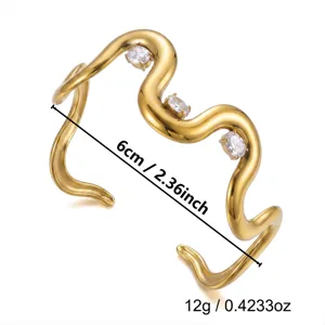 Detailansicht eines wellenförmigen goldenen Edelstahl-Armreifs mit klaren Steinen
