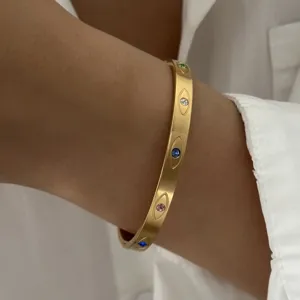 Gedetailleerde opname van een gouden roestvrijstalen armband met gekleurde steenogen