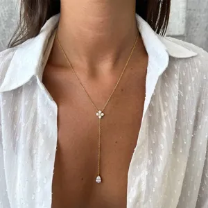 Detail of a minimalist gold Y-shaped necklace with a sparkling stone-paved flower motif.