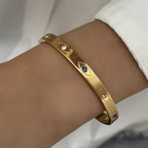 Detailopname van goudkleurige roestvrijstalen armband met gekleurde strass steentjes