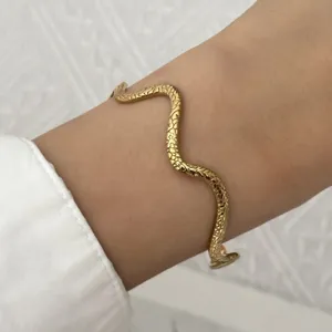 Detailopname van een vintage gouden slangenpatroon gedraaide roestvrijstalen armband