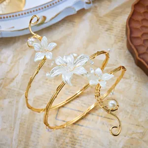 Dettaglio di un bracciale da braccio a spirale dorato con fiori e perle