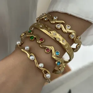 Detail van vintage gouden roestvrijstalen armbanden met parels en gekleurde stenen