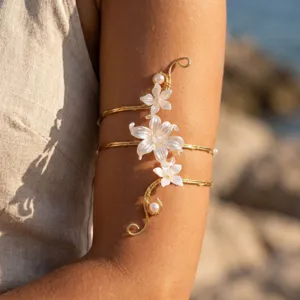 Dettaglio di un bracciale da braccio in filo dorato con fiori bianchi e perle