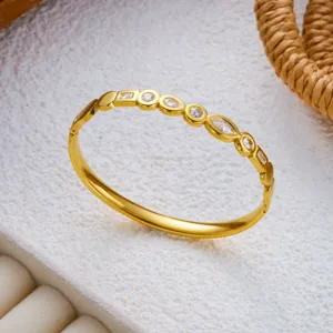 Nahaufnahme eines goldenen Edelstahl-Armreifs mit geometrischen Zirkonia-Einlagen.