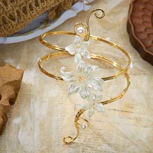 Vista dettagliata del bracciale da braccio dorato con fiori bianchi, perle e spirali