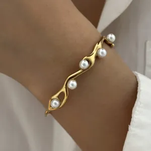 Detailopname van een vintage gedraaide gouden armband met elegante witte parels.