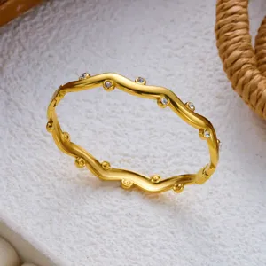 Detaillierte Nahaufnahme eines goldfarbenen, wellenförmigen Armreifs mit funkelnden Kristallen