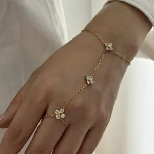 Vue détaillée d'une chaîne de main en acier doré avec des breloques fleurs en zircon.