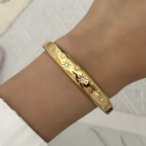 Gedetailleerde macro-opname van een gouden roestvrijstalen armband met sterren en kristallen.