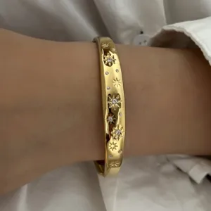Gedetailleerd overzicht van een gouden armband met sterrengravure en kristallen.