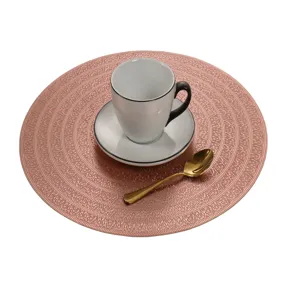 Nahaufnahme Detail einer roségoldenen runden hohlen PVC-Tischset mit Kaffeetasse und Löffel.