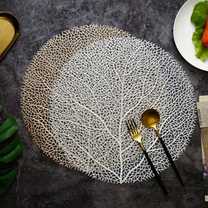 Vista dettagliata della tovaglietta rotonda traforata in PVC con motivo di corallo.