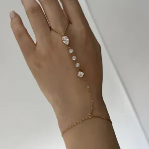 Détail d'un bracelet bague en acier doré orné de pierres en zircone transparentes.