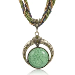Dettaglio di una collana boho vintage con pendente in pietra verde e fili di perline
