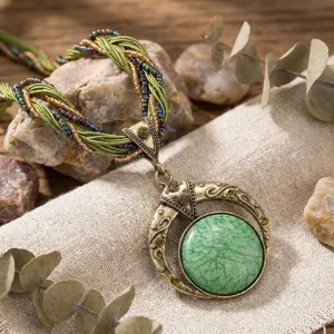 Dettaglio collana bohémien con pietra verde e cordoncino di perline intrecciate