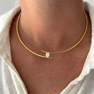 Close-up of a vintage gold open choker necklace with a brilliant oval white stone detail.