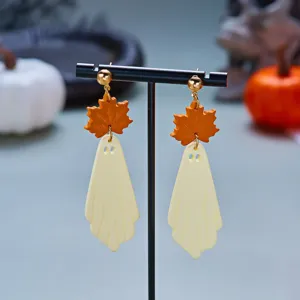 Close-up detail of ghost and maple leaf Halloween drop earrings on a black jewelry stand