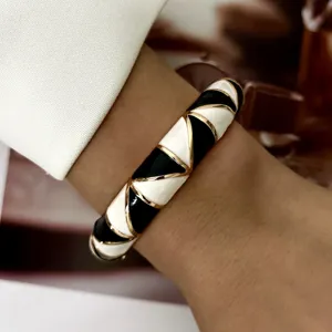 Macro detail of a vintage geometric black and white enamel bangle with elegant gold plating