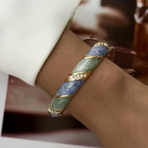 Nahaufnahme eines eleganten blauen Vintage-Emaille-Armreifens mit Strasssteinen am Handgelenk