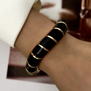 Close-up of retro black enamel bangle with gold stripes on wrist