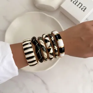 Detailed view of vintage black and white enamel bracelets set with gold-tone accents on wrist