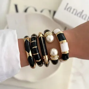 Close-up detail of black and white enamel vintage style bracelets with pearl accents