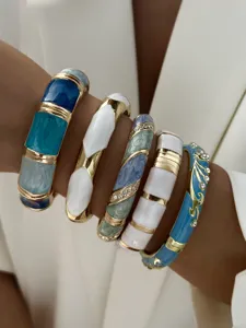 Nahaufnahme von Vintage-Legierungsarmbändern mit blau-weißen Emaille-Mustern und Steinen