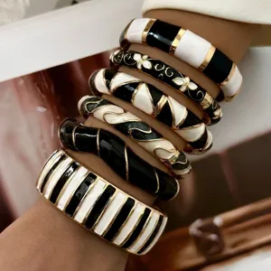 Retro-style black and white enamel bangles with gold-tone accents on a model's wrist