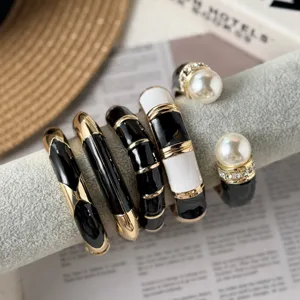 Detailed close-up of black and white enamel bangles with gold trim and pearl accents