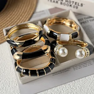 Detail of retro black and white enamel bangles with gold-tone trim and pearl accents.